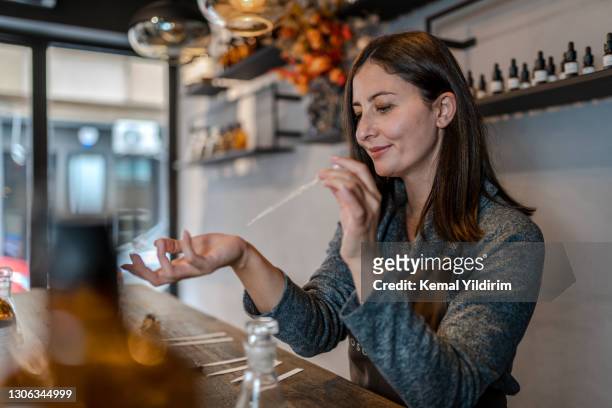 junge parfümierer in vorbereitung parfüm, während am tisch in ihrem eigenen geschäft sitzen - fragrance launch stock-fotos und bilder