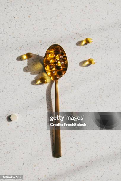 lepel van vitamine d supplementen op een grijze tafel, overhead shot - vitamine d stockfoto's en -beelden
