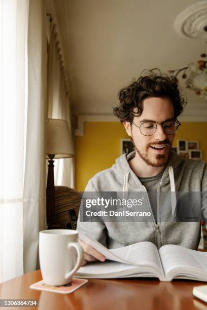 adult surprised student reading book at home - house of ogan stock pictures, royalty-free photos & images