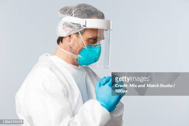 side view of doctor wearing surgical mask against gray background - surgical mask man stock pictures, royalty-free photos & images