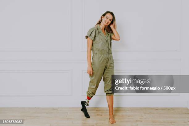 portrait of young woman with prosthetic leg standing against wall - diabetic amputation stock pictures, royalty-free photos & images