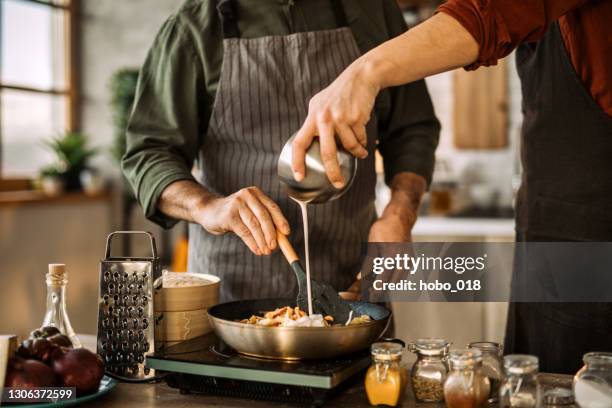 jeune homme apprenant des qualifications de cuisine d’un chef expérimenté. - crème sucrée photos et images de collection