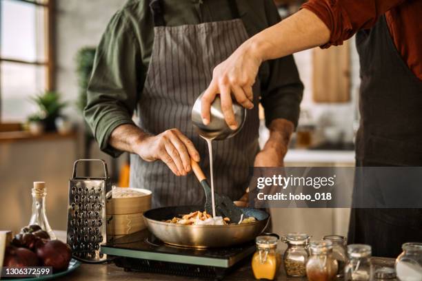young man learning cooking skills from an experienced chef. - creme stock pictures, royalty-free photos & images