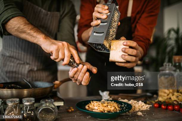 grating hard cheese for best homemade pasta finish - grater stock pictures, royalty-free photos & images