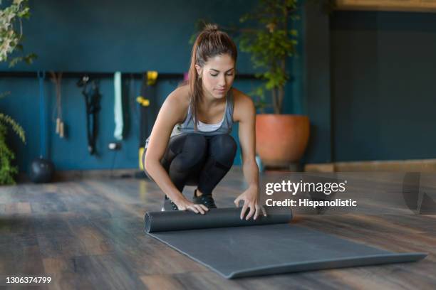 fit woman at a yoga studio rolling up her mat - rolling stock pictures, royalty-free photos & images