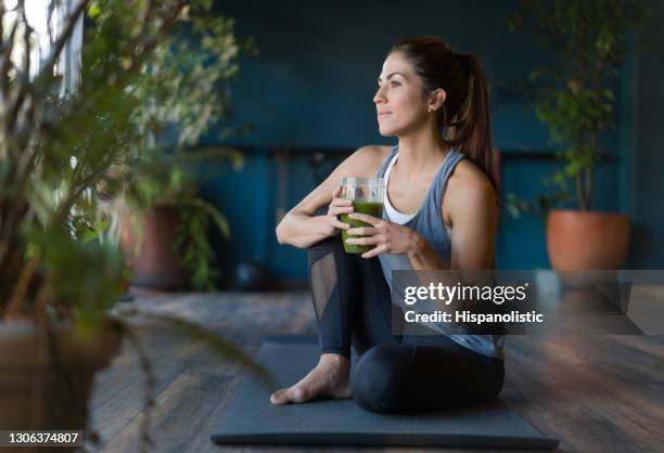 mujer en forma bebiendo un batido de desintoxicación verde en el gimnasio - descansar fotografías e imágenes de stock