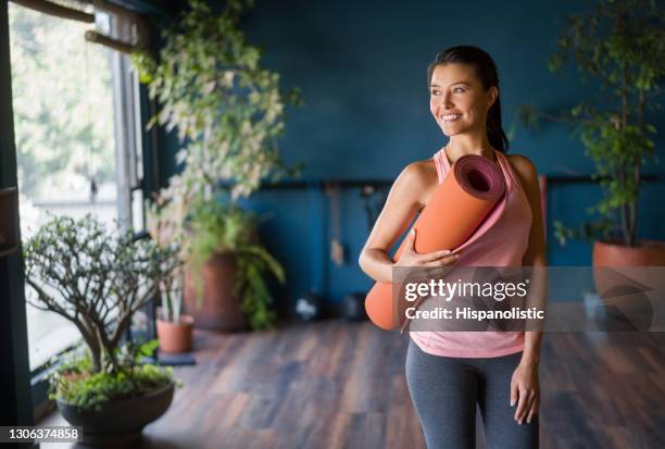 latin american woman at the gym holding a yoga mat - gym reopening stock pictures, royalty-free photos & images