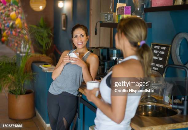 happy women talking at the gym while having a cup of coffee in the cafeteria - cafeteria stock pictures, royalty-free photos & images