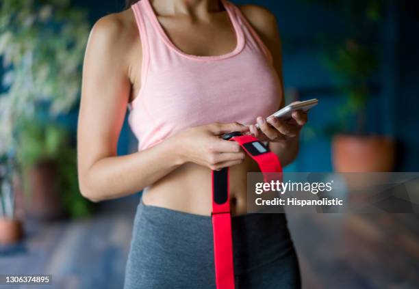 woman at the gym holding her fitness tracker and setting up the app on her cell phone - strap stock pictures, royalty-free photos & images