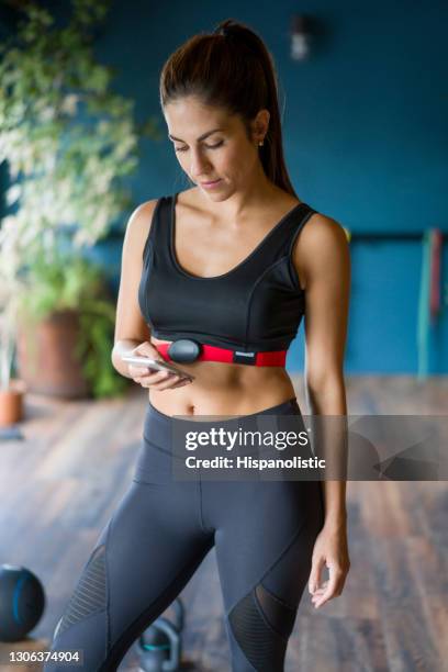 woman at the gym wearing a heart rate tracker and setting up the app on her cell phone - strap stock pictures, royalty-free photos & images