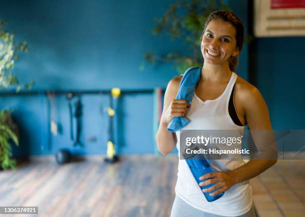 happy woman at the gym holding her towel and a water bottle - gym reopening stock pictures, royalty-free photos & images