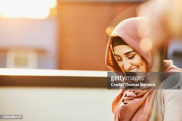 portrait of laughing woman hanging out on rooftop deck on sunny evening - hijab 個照片及圖片檔