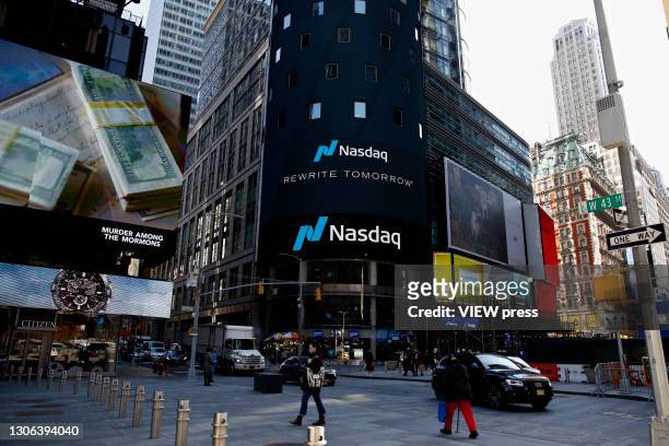 People walk around Nasdaq building at Times Square on March 10 in New York. The Nasdaq Composite continued falling more than half a percent during...