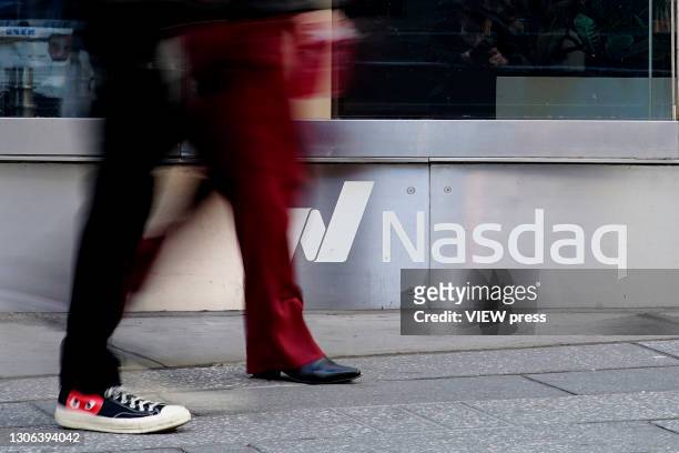 People walk in front Nasdaq at Times Square on March 10 in New York. The Nasdaq Composite continued falling more than half a percent during the day....