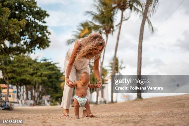 bebé aprende primeros pasos en la playa - mothers day beach fotografías e imágenes de stock