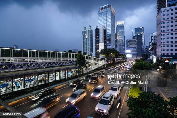 traffic rushing in jakarta business district in indonesia capital city at twilight - newly industrialized country stock pictures, royalty-free photos & images