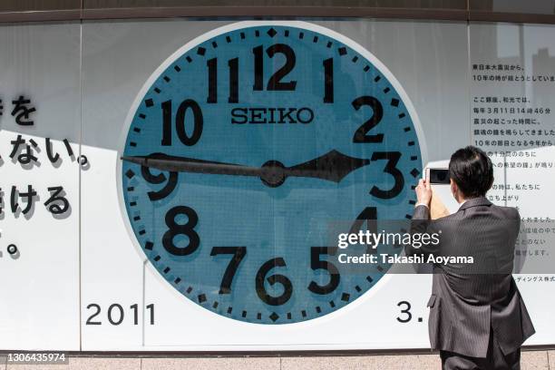 Man takes a photograph of a large display showing 14:46, the time that the 2011 Tohoku earthquake hit, on March 11, 2021 in Tokyo, Japan. Japan will...