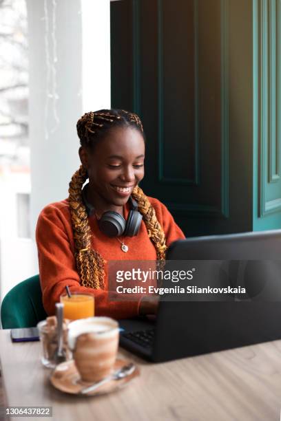 close-up portrait of young african woman using laptop in cafe. - business headphones stockfoto's en -beelden