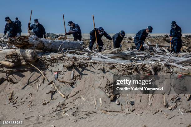 Police officers search for the remains of people who went missing after the 2011 Tohoku earthquake and tsunami on March 11, 2021 in Namie, Japan....