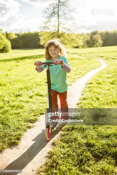 cute girl with red hairs in a park. - girl riding scooter stock pictures, royalty-free photos & images