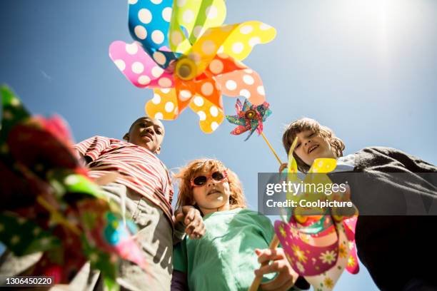 multiethnic group of children with pinwheels on a meadow - moinho de papel - fotografias e filmes do acervo