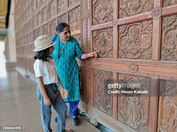 grandmother explains the religious faiths behind the wooden engravings on the huge door at pagoda - indian temples stock pictures, royalty-free photos & images