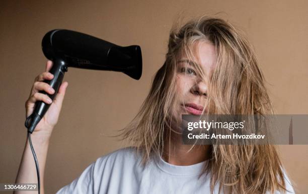 serious woman with black hairdryer - hair dryer - fotografias e filmes do acervo