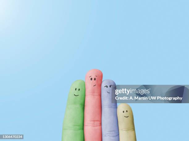 fingers with painted faces on blue background colored in different color. metaphor of a multiethnic family. - happy face drawing stock pictures, royalty-free photos & images