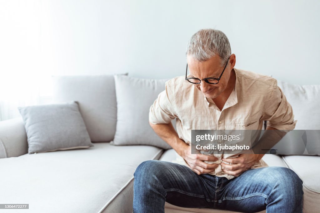 Mature man suffering from stomachache at home