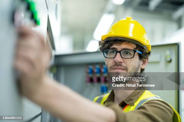 a male maintenance engineer working at electricity control room of solar cell power plant while monitoring, conducts a safety in front of a control panel. electronic, monitoring, prevention system concepts. - electrical switch stock-fotos und bilder