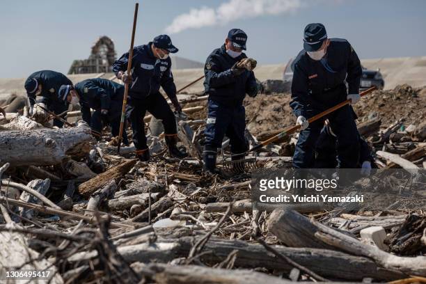 Police officers search for the remains of people who went missing after the 2011 earthquake and tsunami on March 11, 2021 in Namie, Japan. Japan will...