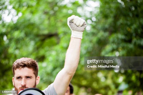 primer plano del joven voluntario que habla en megáfono en el parque - puño en alto fotografías e imágenes de stock