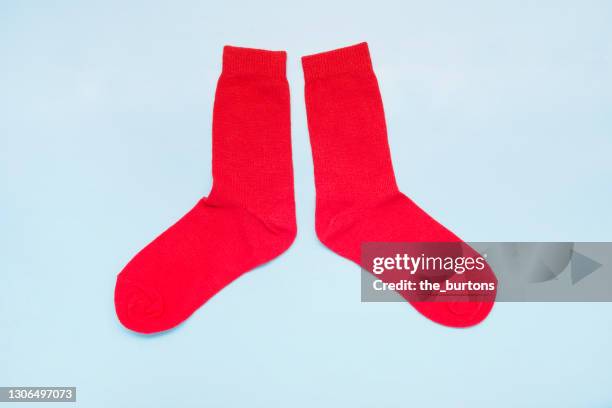 still life of a pair of red socks on blue background - paio foto e immagini stock