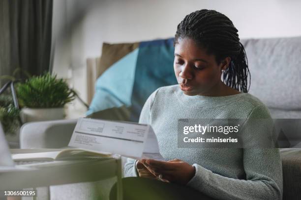 women in business: a young businesswoman reading a utility bill while working from home - energy bill stock pictures, royalty-free photos & images