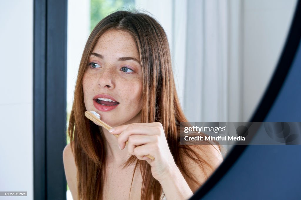 Close up of young woman brushing her teeth at home
