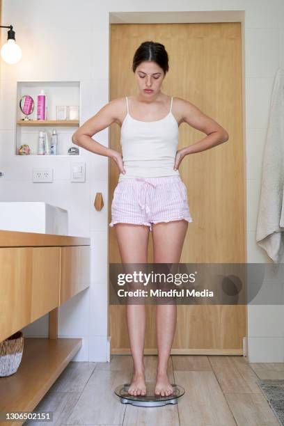 jeune femme se pesant sur une échelle - anorexie nerveuse photos et images de collection