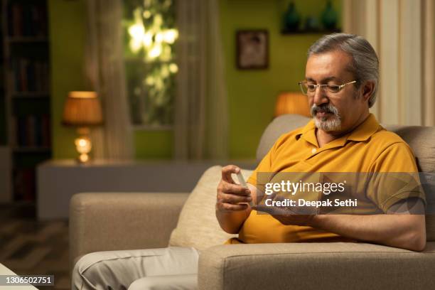 mature men with glucometer checking blood sugar level at home:- stock photo - man examining stock pictures, royalty-free photos & images