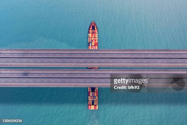 container freight ship passing under bridge - container ship stock pictures, royalty-free photos & images