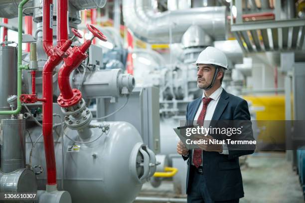 a portrait of ceo standing in a corridor of boiler control room and holding a digital tablet. - pipes and ventilation stock pictures, royalty-free photos & images