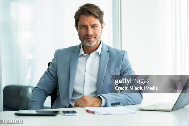 portrait of contented businessman sitting in office - ceo desk imagens e fotografias de stock