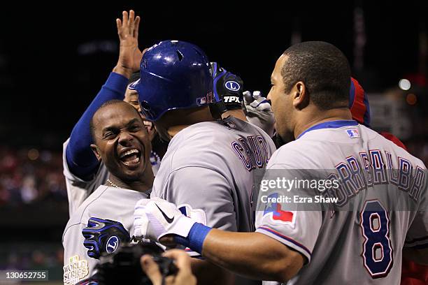 Nelson Cruz of the Texas Rangers celebrates with Esteban German and Yorvit Torrealba after hitting a solo home run in the seventh inning during Game...