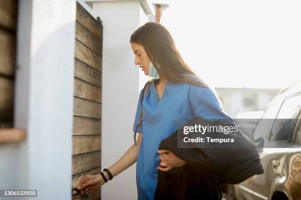 eine krankenschwester, die nach hause kommt und die haustür öffnet. - woman entering home stock-fotos und bilder