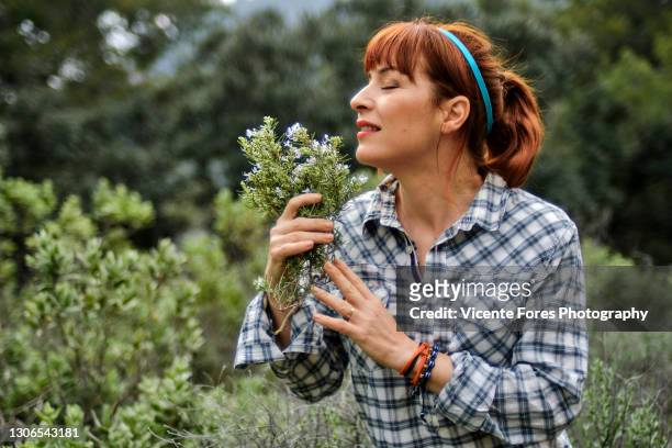 redhead girl smelling a rosemary with a squared shirt - relajación photos et images de collection