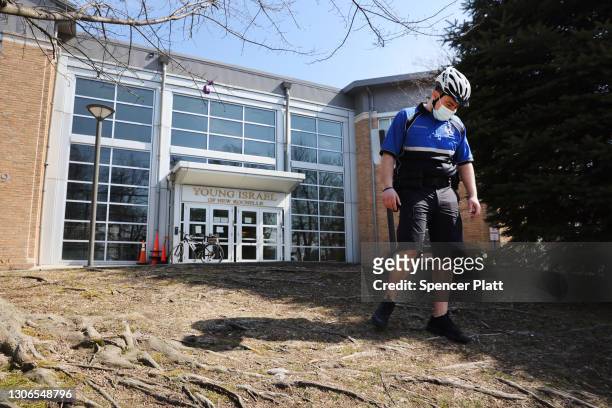 Police officer walks in front of the Young Israel synagogue where the first Covid cases were traced in the city of New Rochelle on March 11, 2021 in...