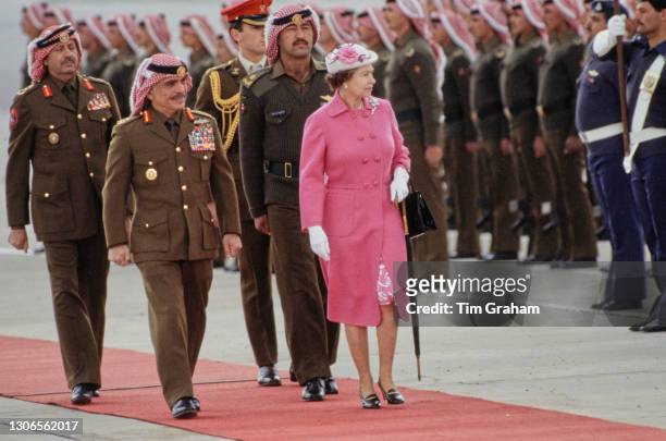 Jordanian Royal King Hussein of Jordan , in military uniform, and British Royal Queen Elizabeth II, who wears a pink coat and white hat with a floral...