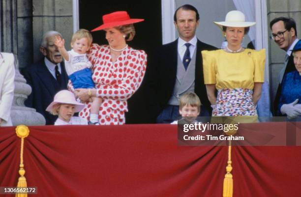 British Royals Diana, Princess of Wales - wearing a red polka dot dress from Tatters of London with a red wide-brim hat - holding her son, Prince...