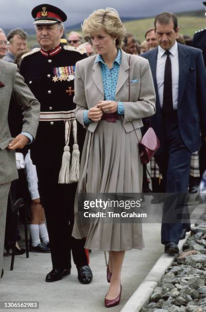 British Royal Diana, Princess of Wales, wearing a turquoise and red polka dot shirt with a beige, pleated skirt suit, with unspecified dignitaries...