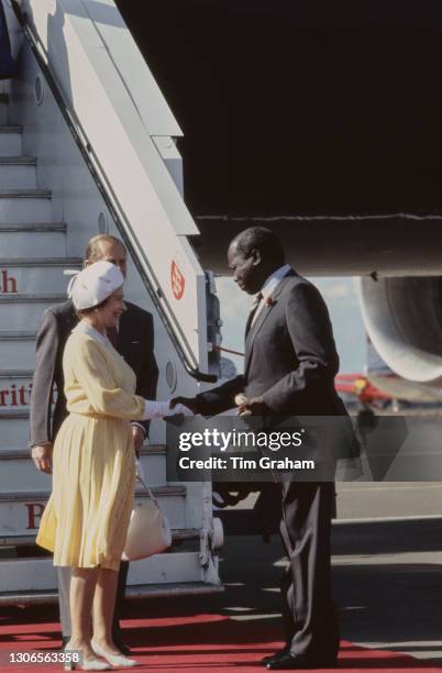 British Royals Prince Philip, Duke of Edinburgh and Queen Elizabeth II, wearing a yellow dress with a white collar, white evening gloves and a white...