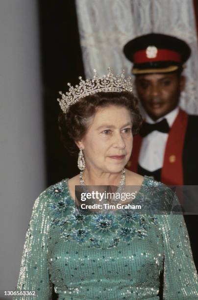 British Royal Queen Elizabeth II, wearing a green dress with a tiara, necklace and earrings, a Kenyan guard in the background, during a State banquet...