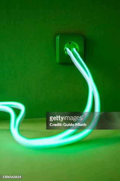 clean green energy out of plug socket. - umweltfreundliche energieerzeugung stock-fotos und bilder